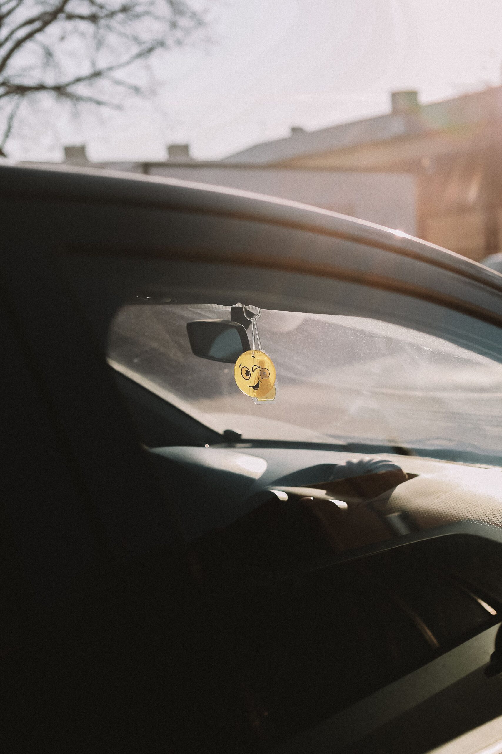 Windschutzscheibe eines Autos mit Smiley-Anhänger am Rückspiegel