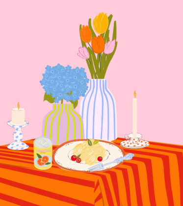 Ein bunt gedeckter Tisch mit Pastateller, Limonade, bunten Blumenvasen und Kerzen